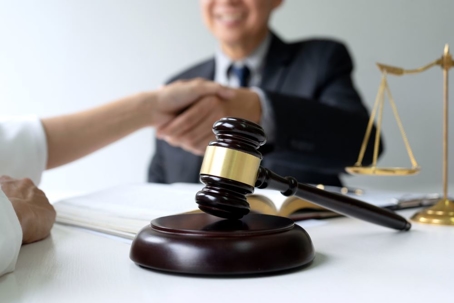 Lawyer or judge with gavel and balance handshake with client