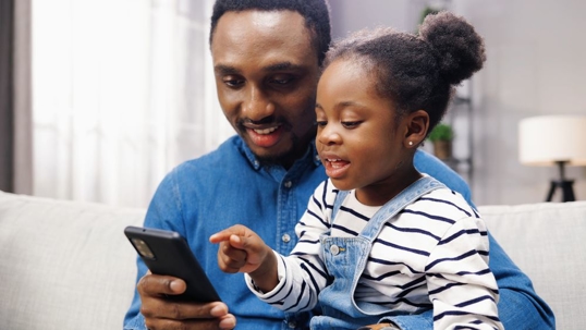 child sitting with father on couch in living room